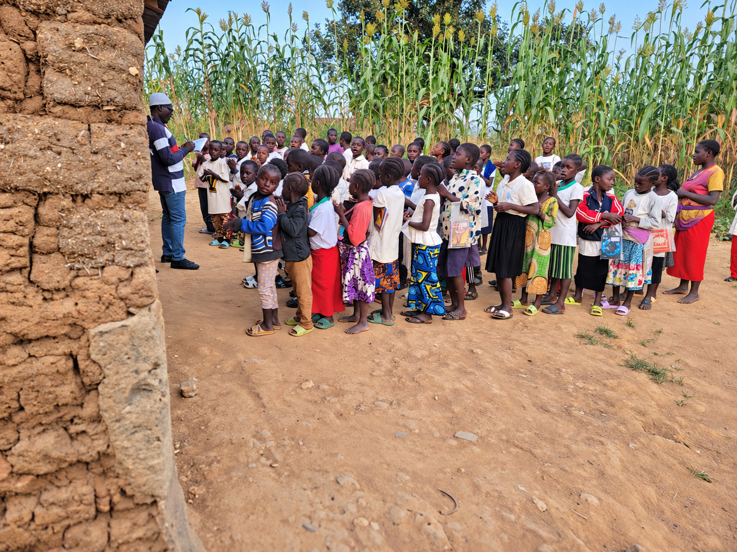Children gathered with a teacher outside a school building.