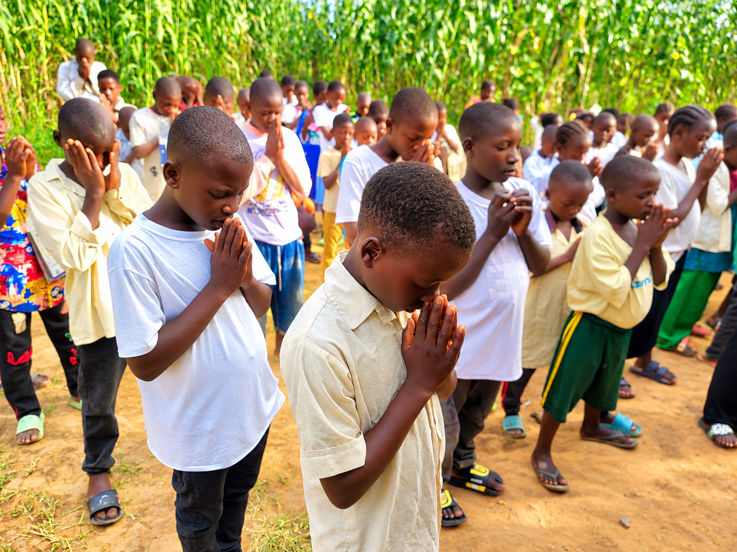 Children gathered outdoors in prayer.